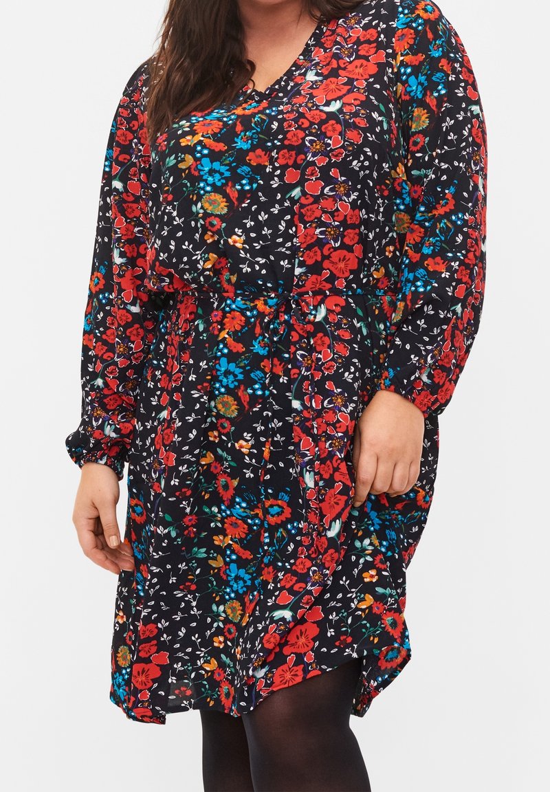 Blumenkleid aus schwarzem Stoff mit lebhaften roten, blauen und grünen Blumen. Es hat lange Ärmel, einen V-Ausschnitt und einen Taillengürtel.