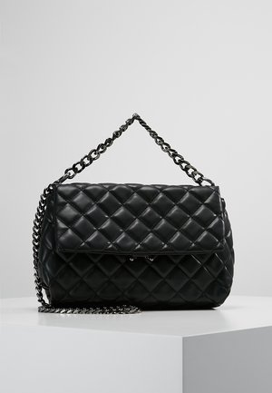 Black quilted leather handbag with flap closure and thick metal chain strap resting on a white surface against a gray background.