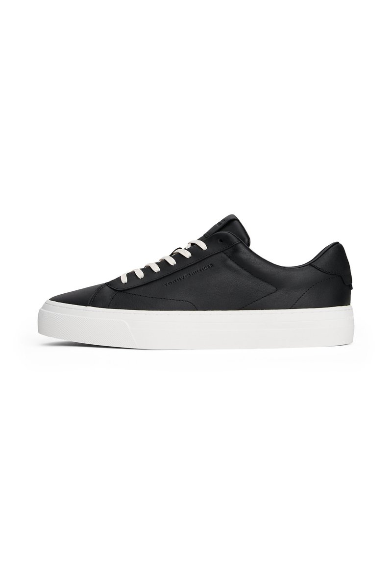 Adidași negri din piele cu talpă din cauciuc albă, bot rotund și șireturi albe contrastante. Prezintă un design minimalist și cusături tonale.