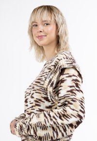 Stickad tröja med ett vågigt mönster i brunt och kräm, strukturerat material, oversized passform och sänkta axelsömmar.