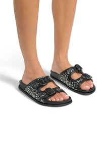 Zwarte slide sandalen met twee verstelbare gespen, versierd met zilveren studs en strassstenen, met een platte zool en open teen ontwerp.