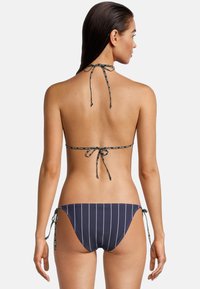 Zestaw bikini w kolorze granatowym z białymi paskami; top halter z zapięciem na sznurek oraz regulowane majtki z wiązaniami po bokach. Gładki, elastyczny materiał.