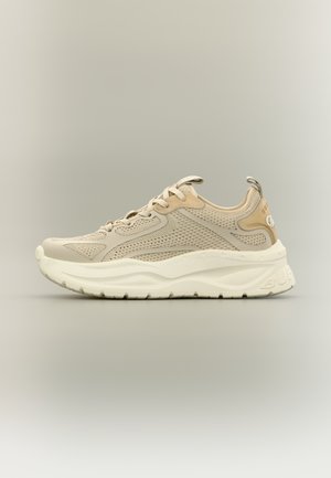 Beige színű hálós sportcipő vastag fehér talppal, fűzős kialakítással és húzófüllel a saroknál, sima semleges háttéren bemutatva.