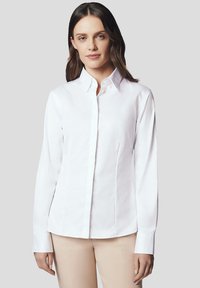 Biała dopasowana koszula z kołnierzykiem, długimi rękawami i zapinana na guziki. Gładka bawełniana tkanina, dopasowany krój oraz subtelne szwy dla uzyskania kształtu.