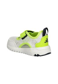 Sneaker bianca in rete con dettagli verde fluo, cinturino regolabile e suola testurizzata. Presenta sezioni ritagliate per traspirabilità e comfort.