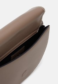 Clutch-Tasche aus glattem, taupefarbenem Leder mit kontrastierendem schwarzen Innenfutter. Verfügt über sichtbare Nähte entlang der Kanten und ein Logoschild im Inneren.