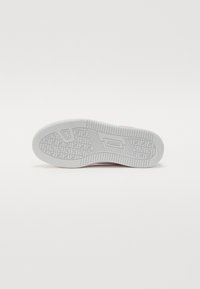 Puma-såle med et teksturert hvitt gummidesign, med et mønstret grep og en sentral logo. Glatte kanter og holdbar konstruksjon.