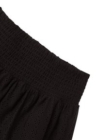 Gonna nera con vita arricciata, motivo a occhietti e un design morbido e raccolto. Realizzata in tessuto leggero.