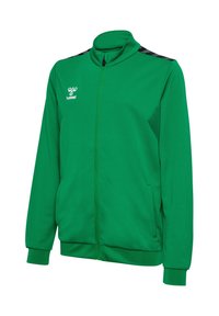 Zielona sportowa kurtka z pełnym zamkiem błyskawicznym, czarnymi paskami w kształcie jodełki na ramionach, dwoma bocznymi kieszeniami, żebrowanymi mankietami i dołem oraz białym logo hummel na piersi.