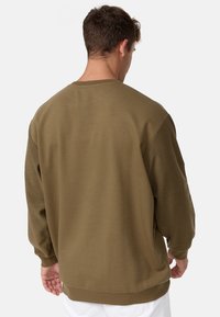 Olivgrüner Sweatshirt mit lockerer Passform, Rundhalsausschnitt und langen Ärmeln. Strukturierter Stoff und gerippte Bündchen am Saum und an den Ärmeln.