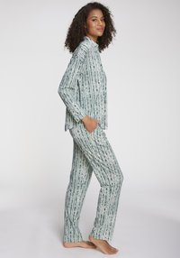 Grön och vitrandig pyjamasset tillverkat av mjukt tyg, med krage, långa ärmar och raka byxor med fickor.