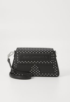 Black leather handbag with silver polka dots, structured design, adjustable shoulder strap, and embossed logo at the front.