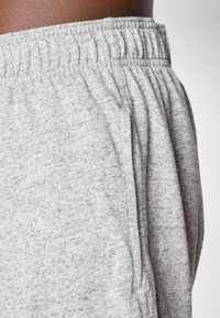 Gray cotton blend joggers with an elastic waistband and side pockets. Fabric has a soft texture with a heathered pattern.