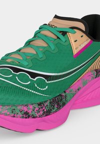 Chaussure de course verte et beige avec des lacets turquoise, un logo noir et blanc, et une semelle rose avec un motif tacheté noir et vert.