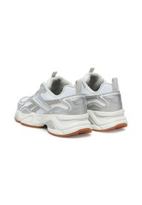 Fehér hálós és ezüst szintetikus sportcipők vastag, párnázott talppal és hangsúlyos gumi talppal. Tartalmaz megerősített sarkat és kiemeléseket.