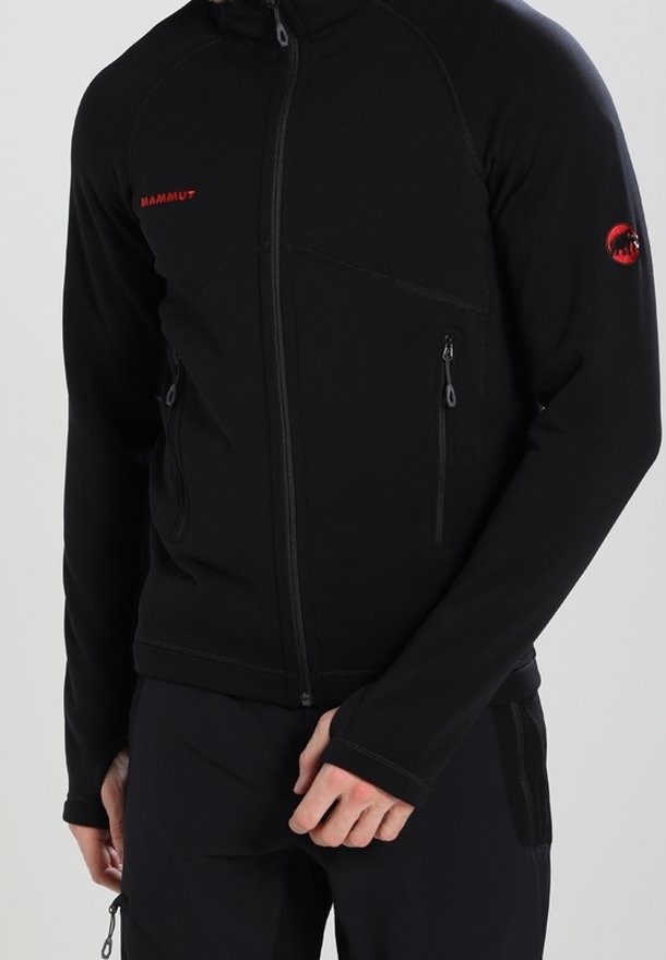Man med svart zip-up Mammut-jacka med två zippered fickor och röda logotyper på bröstet och ärmen.