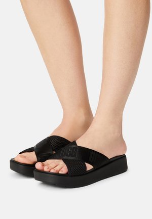 Sandalias de plataforma negras con diseño de tiras cruzadas. Fabricadas con malla suave y tela con la marca UGG. Suela gruesa de goma con acabado texturizado.