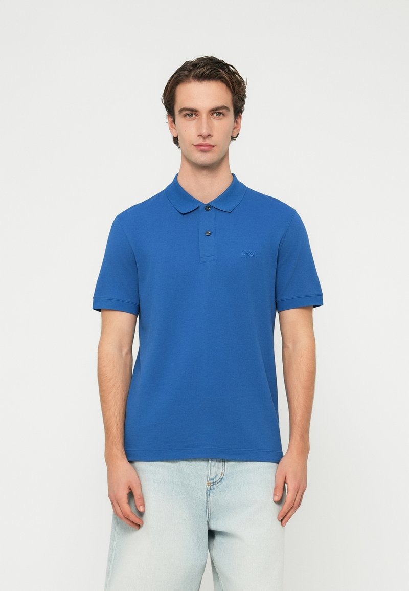 Μπλε πόλο πουκάμισο από απαλό βαμβάκι, με κλασικό γιακά, κοντά μανίκια και 3 κουμπιά στην πατιλέτα. Διακριτικό λογότυπο στο στήθος.