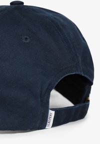 Navy blue corduroy cap featuring a curved brim, adjustable strap, and a small label with "SCALPERS" on the side. Textured surface.