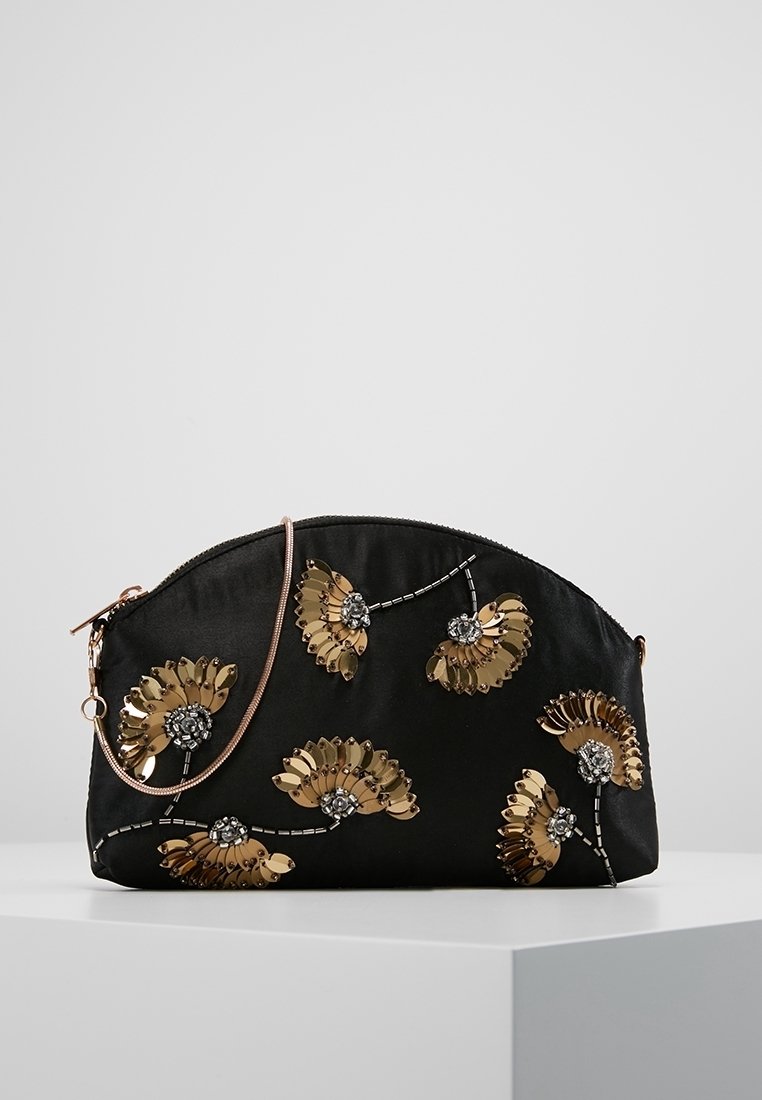 Zwarte halfronde clutch met gouden bloemenmotieven van pailletten en kleine steentjesversieringen, voorzien van een dunne roségouden band, op een witte ondergrond.