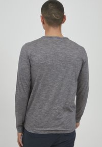 Langærmet grå T-shirt med et struktureret mønster. Rund halsudskæring, lige kant og tætsiddende ærmer. Minimalistisk design uden synlig branding.