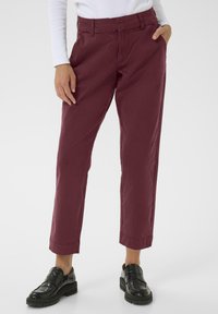 Burgundy cotton pants with a relaxed fit, cropped length, and side pockets, paired with black leather slip-on shoes.