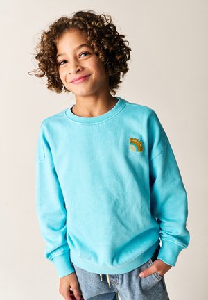 Turkis sweatshirt lavet af blødt stof med rund hals og lange ærmer. Har et lille orange og blåt grafisk motiv på brystet.