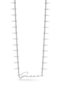 Collier chaîne en argent orné de pompons blancs décoratifs et d'un logo "Guess" en écriture cursive. Le design allie élégance et esthétique moderne.
