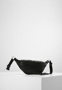 Czarna skórzana torebka na ramię o trójkątnym kształcie, z zamkiem błyskawicznym i regulowanym paskiem. Gładka faktura i minimalistyczny design.