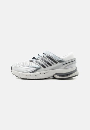 Chaussure de sport blanche et grise avec tige en mesh, plusieurs sangles, semelle rembourrée et détail de marque sur le côté, présentée en profil gauche sur un fond clair.