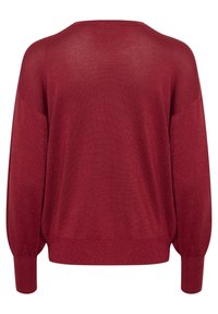 Pull en maille bourgogne à coupe ample, avec des manches larges et des poignets côtelés. Le matériau a un subtil éclat, créant un aspect texturé.