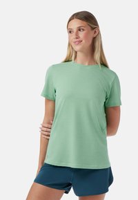 T-shirt de sport texturé à manches courtes, vert clair, avec col rond et coupe décontractée, associé à un short bleu marine.