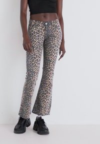 Pantalons évasés en imprimé léopard dans des tons de beige et de marron, avec une fermeture à bouton, des poches avant et une texture en denim lisse.