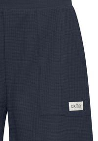 Donkerblauwe shorts van een gestructureerde stof met een patch pocket en een label met de merknaam. Het ontwerp is casual en functioneel.