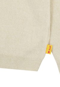 Hellbeige gestrickter Pullover mit gerippten Bündchen. Mit einem kleinen gelben Etikett mit Bärenlogo am Saum. Weiche Textur, klassische Silhouette.