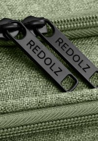Grüne Stofftasche mit schwarzen Reißverschlüssen und dem Aufdruck "REDOLZ", die ein strukturiertes gewebtes Material und ein glattes Reißverschlussdetail zeigt.