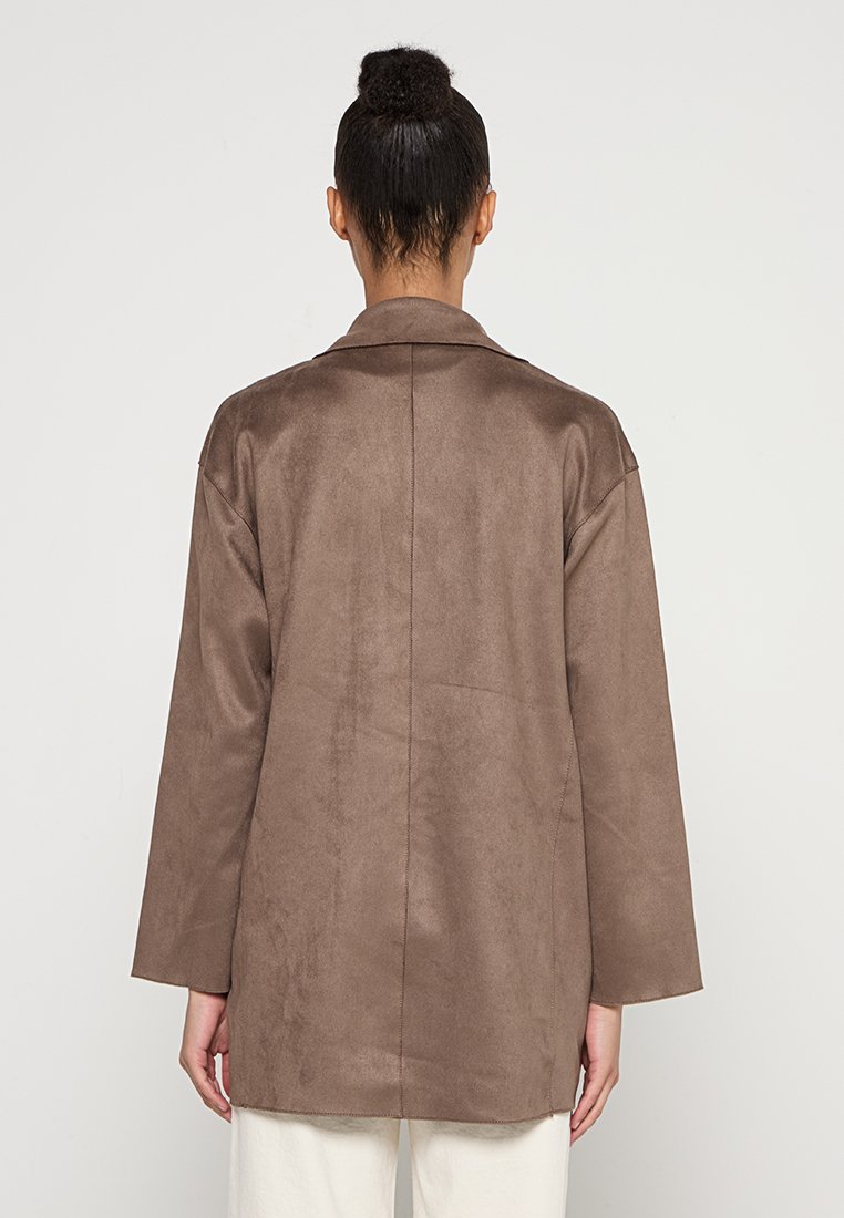 Cappotto lungo marrone, a maniche lunghe, realizzato in un materiale morbido simile alla pelle scamosciata, con colletto a punte e taglio diritto, caratterizzato da dettagli di cucitura minimi.