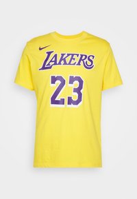 Gul bomullst-shirt med "LAKERS" i lila och "23" i vitt med lila accenter; rund hals och korta ärmar.