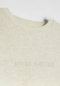 Jasnoszara, teksturowana bawełniana bluza z ribbingu, z okrągłym dekoltem i wytłoczonym napisem "DIVERSE ATHLETICS" na środku przodu.