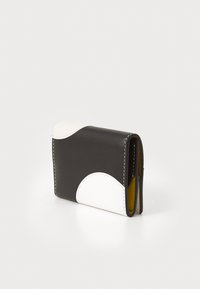 Kompakte Geldbörse aus schwarzem Leder mit weißen, geschwungenen Akzenten, gelbem Innenfutter und sichtbaren Nähten. Rechteckige Form mit glatter Textur.