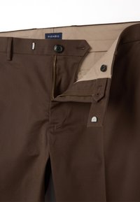 Bruine broek met een gladde textuur, voorzien van een rits- en knoopsluiting, lichtbeige voering en een logo-label.