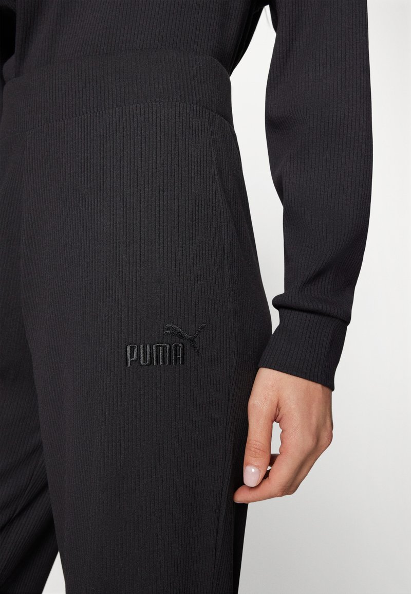 I pantaloni jogger neri a coste presentano una vita elastica e un logo Puma ricamato. Vista ravvicinata che evidenzia la texture e i dettagli del design.
