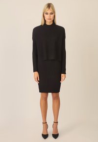 Abito a due pezzi nero composto da un top cropped a coste con maniche lunghe e una gonna midi a coste aderente. Vestibilità slim e tessuto morbido.