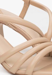 Beige haksandalen met meerdere smalle banden, een gladde lederen textuur, een gesloten teenontwerp en een minimalistische esthetiek.