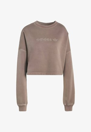 Felpa cropped in morbido tessuto taupe. Presenta un collo rotondo, maniche lunghe e il logo "adidas" in rilievo sul fronte. Texture liscia.