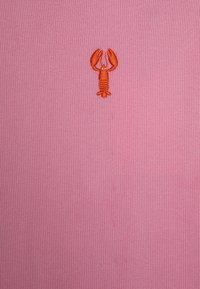 Rosa ribbet stoff med en liten oransje brodert hummerdesign plassert sentralt. Teksturen er glatt med fremtredende vertikale linjer.
