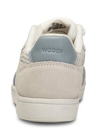 Sneaker grigio chiaro con tomaia in suede e tessuto intrecciato, dettagli blu tonalità, colletto imbottito e suola in gomma bianca. Nome del brand "WODEN" impresso sul tallone.