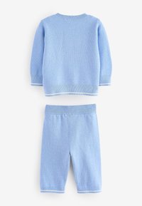 Světle modrý bavlněný pletený dvoudílný komplet, který zahrnuje svetr s kulatým výstřihem a kraťasy, oba s kontrastním bílým lemováním na manžetách a pase.