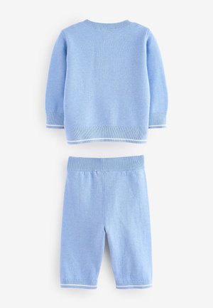 Vaaleansininen puuvillaneuleesta valmistettu kaksiosainen asu, joka koostuu pyöreäkauluksisesta neulepuserosta ja shortseista, molemmissa valkoiset kontrastireunukset hihoissa ja vyötäröllä.