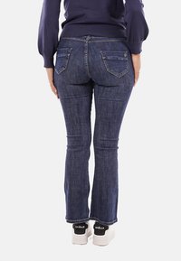 Jeans blu scuro con una vestibilità slim, con vita media, tasche posteriori con dettagli di cucitura e leggere sfilature nei bordi.